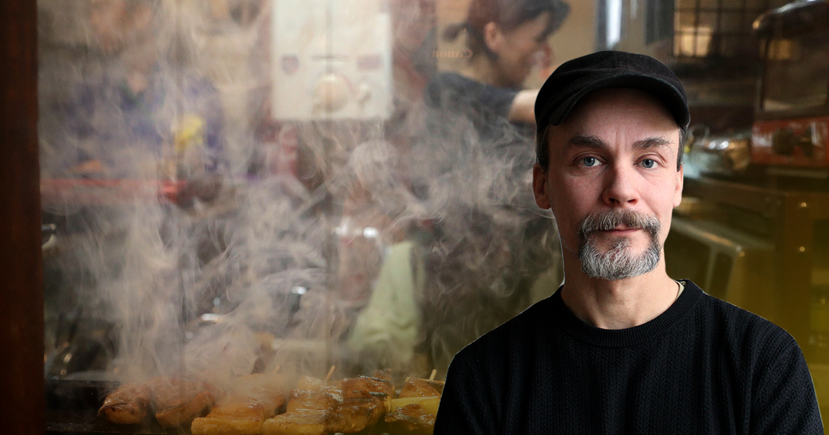 Emil Boss i svart tröja och keps mot bakgrund av restaurangarbetare